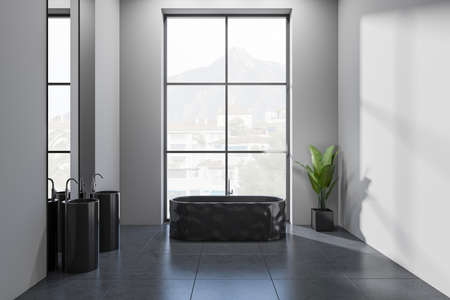 Front view on dark bathroom interior with bathtub, panoramic window with town view, mirror with reflection, sinks, houseplant, gray walls. 3d renderingの写真素材