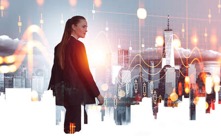 Businesswoman smiling and walking, double exposure of New York Manhattan, stock market candlesticks and forex diagrams. Concept of finance and analysisの写真素材