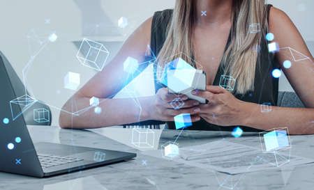 Businesswoman hand typing in phone, laptop with contract on desk. Digital hologram of information...