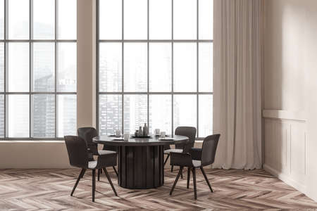 Beige dining room interior with black table and dishes, chairs on hardwood floor. Panoramic window...
