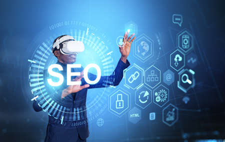 Black businessman in vr headset hands touch search engine optimization hologram. Ranking traffic and website promoting tools, glowing chain of icons. concept of marketingの写真素材