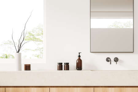 White bathroom interior with sink and mirror, vase with dried flower and soap bottle on beige...