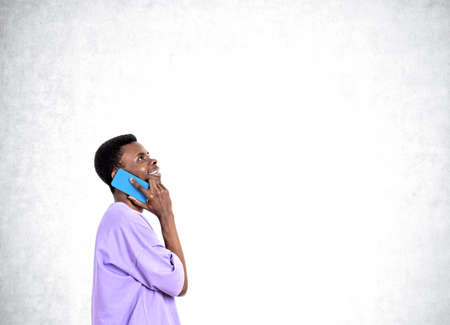 African American handsome businessman wearing casual wear is talking on smartphone near empty...