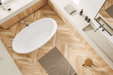 Top view of white bathroom interior with bathtub on hardwood floor. Washing corner with sink and...