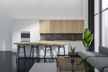 White studio interior with eating area, bar island and chairs, carpet on dark concrete floor. Sofa with coffee table and panoramic window on city view. 3D renderingの写真素材