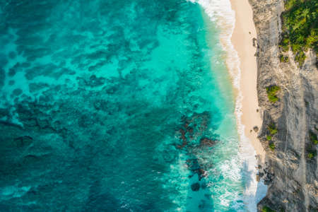 Aerial drone top view shot of rocky beach with cliff. Indian ocean shore. Copy space for text. Nature and travel background. Beautiful natural summer vacation travel concept. waves and sand.の写真素材