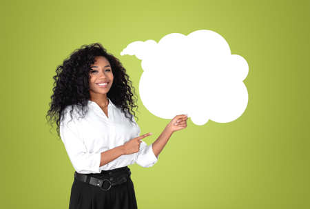 African American businesswoman wearing formal wear is standing pointing up with fingers to speech...