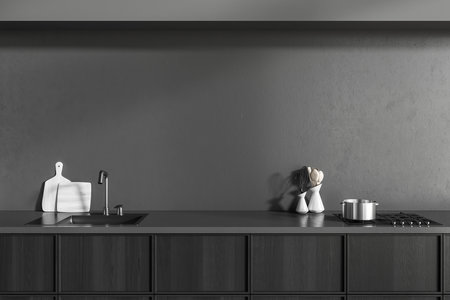 Close up view on dark kitchen room interior with cupboard, gray empty wall, sink, gas cooker, spoon, cooking desks. Concept of minimalist design. 3d renderingの写真素材