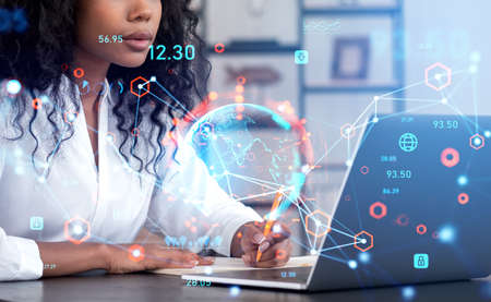 Black businesswoman taking note and looking at laptop. Globe hologram connection hologram. Metaverse...