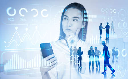 Group of business people work together. commercial firm. Pondering businesswoman holding smartphone touching chin. Hud hologram with financial graphs, pie and bar diagrams. Concept of stock analysisの写真素材