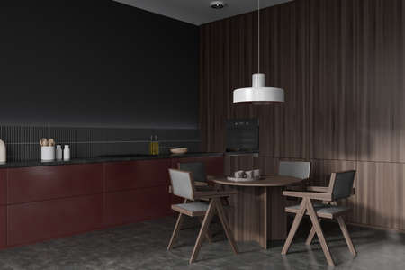 Dark kitchen interior with chairs and dining table, side view, gray concrete floor. Kitchenware and appliances on deck, oven mounted. Hidden shelves design. 3D renderingの写真素材