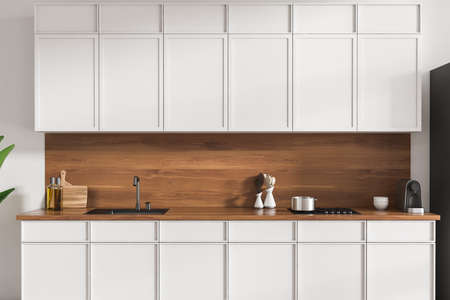 White kitchen interior with sink, stove and minimalist kitchenware. Cooking area in hotel studio, 3D...