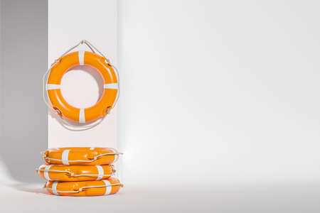 Orange lifebuoys hanging on white wall, stack of life saving rings. Concept of rescue and beach. copy spaceの写真素材