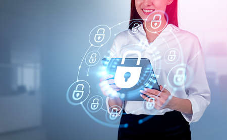 Smiling businesswoman working with tablet in hands, cybersecurity lock chain hologram with glowing digital icons. Concept of data protectionの写真素材
