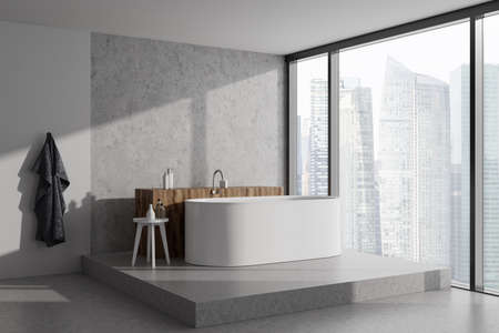 Stylish bathroom interior with bathtub on podium with bath accessories, side view. Panoramic window...