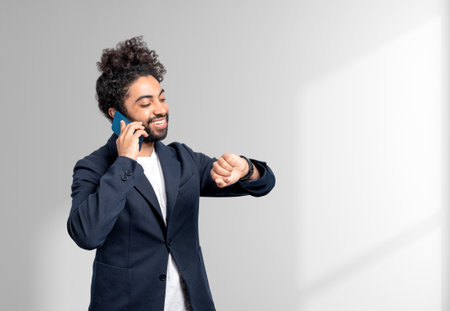 Arab businessman portrait smiling and calling on the phone, checking the time. Copy space white...
