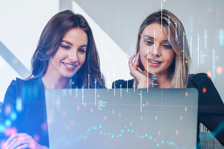 Two office woman looking at computer, smiling portraits. Double exposure with stock market hologram...