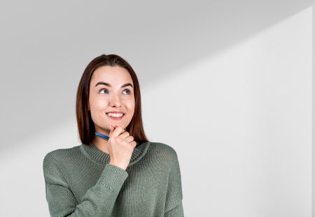 Smiling and inspired woman with look up and hand to chin, copy space empty white background. Concept...
