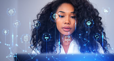 Black woman using laptop, double portrait exposure with virtual screen and internet of things (IOT). Glowing icons of modern technology and AI. Concept of smart home and connectivityの写真素材