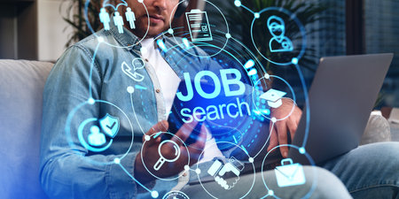 Man searching for job online, smartphone and laptop with glowing circle hologram with business icons. Recruitment in company and video interview. concept of employmentの写真素材