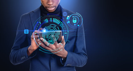 African businessman working with tablet, glowing fingerprint hud hologram with cybersecurity and...