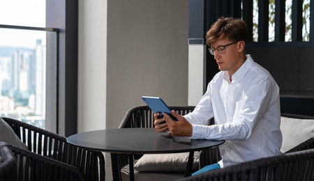 Concentrated businessman using tablet for online shopping and business in internet, sitting at cafe....