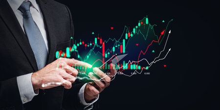 Hands of unrecognizable businessman using smartphone with financial graph over dark blue background....