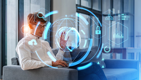 Young European businessman using laptop sitting on office sofa with double exposure of metaverse and...