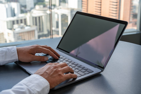 Side view of businessman hands typing on laptop, city skyscrapers on background. Mock up copy space...
