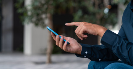 Businessman finger pointing, touching smartphone closeup on blurred background. Man hands with phone, browse internet and online shopping. Concept of payment and buyの写真素材