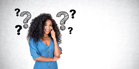 Black young woman with dreaming and happy look, finger on temple thinking. Doodle question marks on...