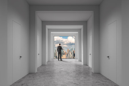 Rear view of young businessman with folder looking at city skyline through panoramic office window. Concept of leadership, business goals and successful strategy developmentの写真素材