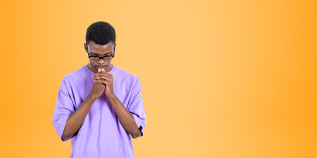 Portrait of young African man college student in casual clothes and glasses thinking hard standing over orange background. Concept of planning and career choice. copy spaceの写真素材