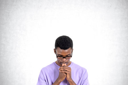 Portrait of young African man college student in casual clothes and glasses thinking hard standing over concrete background. Concept of problem solving and career choiceの写真素材