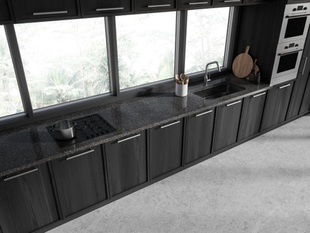 Top view of dark home kitchen interior cabinet with sink, stove and oven mounted. Minimalist...