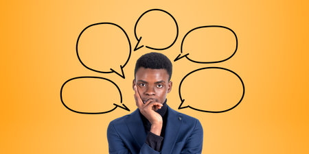 Portrait of thoughtful young African American businessman standing with hand on chin over orange...