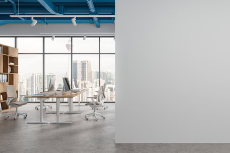 Stylish coworking interior with pc monitors on table in row, shelf with documents and clock. Panoramic window on Kuala Lumpur skyscrapers. Mockup copy space wall partition. 3D renderingの写真素材