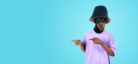 Man with Dobermann dog head fingers pointing to the side, copy space empty background. Concept of offer, recommendation, business advice and advertisementの写真素材