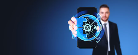 Businessman showing smartphone display with bank vault safe glowing hologram, empty copy space dark background. Concept of online protection, data security and business safetyの写真素材