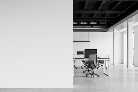 Stylish office interior with pc computers on desks and armchairs, concrete floor. Minimalist coworking space with panoramic window on skyscrapers. Mockup empty wall. 3D renderingの写真素材