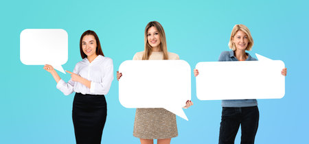 Three women holding blank speech bubble signs on a light blue background. Communication concept