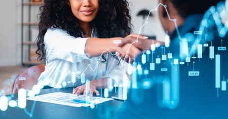 Black businesswoman smiling and shaking hands with businessman. Double exposure of forex diagrams,...