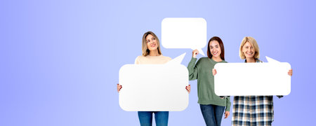 Three happy women portraits holding mock up signboard, speech or thought bubbles on copy space purple background. Concept of opinion, recommendation and feedbackの写真素材