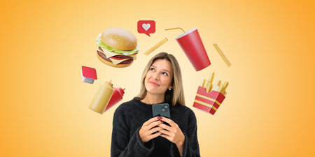 Woman with smartphone in hands, looking up at cartoon burger with fries, drink and sauce on empty...