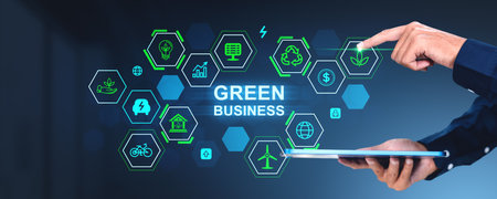 Businessman using tablet, finger touch green business glowing hologram icons cells in row. Concept of investment environment, futuristic technology and renewable resourcesの写真素材