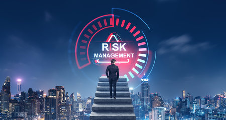 Businessman climbing stairs towards a Risk Management hologram. Cityscape background at night. Concept of business challenge and risk assessmentの写真素材