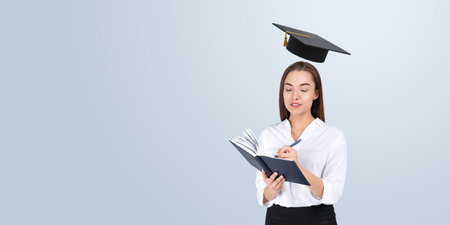 Serious businesswoman taking notes, graduation cap above her head. Copy space empty background. Concept of education, university, startup, future idea and careerの写真素材