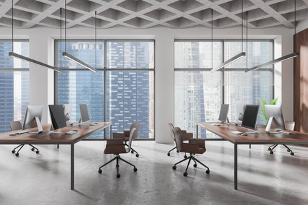 Modern open-plan office with computers on wooden desks, ergonomic chairs, and large windows overlooking a city skyline, concrete ceiling. 3D Renderingの写真素材