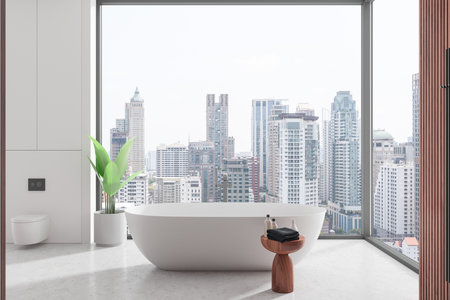 Modern bathroom with a freestanding bathtub facing a large window overlooking a city skyline,...