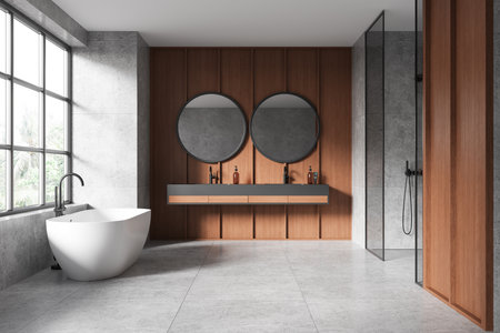 Wooden and gray hotel bathroom interior with bathtub, double sink and shower, gray tile concrete floor. Open space batting area with panoramic window on tropics. 3D renderingの写真素材